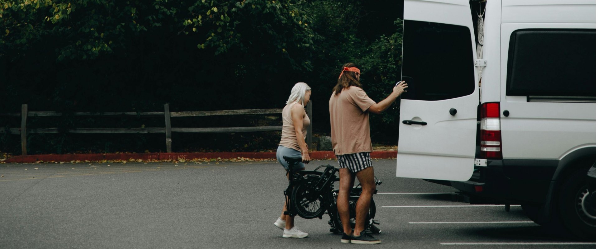 A landscape photo with two people loading a bike into a caper