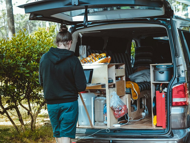 Een foto van een dame die aan een laptop werkt buiten een camper