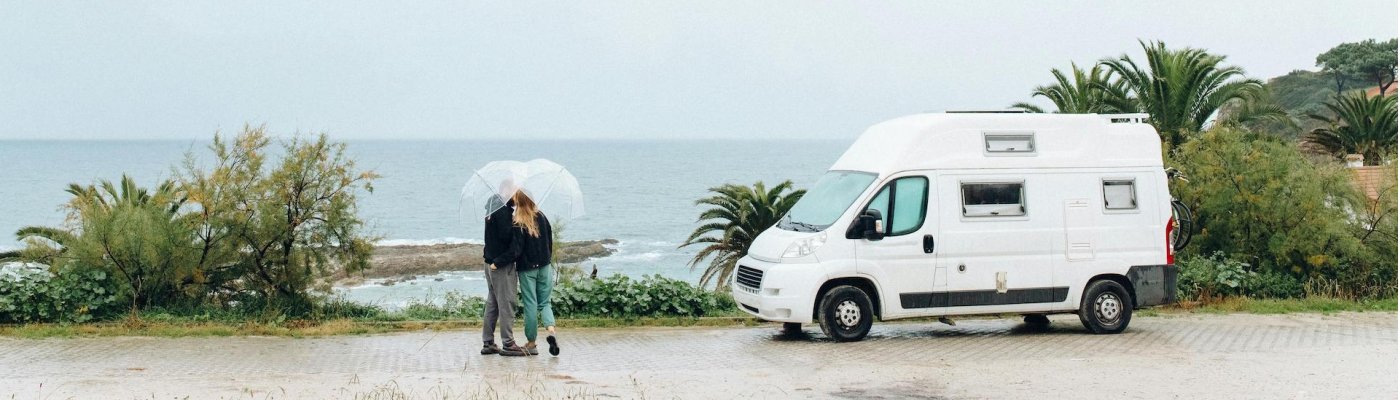 Bannerafbeelding van twee personen en een camper met uitzicht op zee